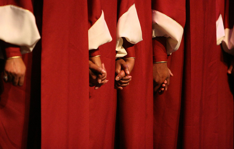 Group of people in red and white robes holding hands